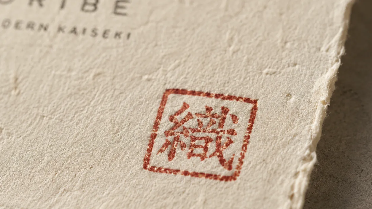 The Oribe red square stamp — a hand-pressed signature on cream washi paper